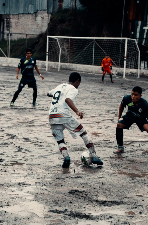 a group of young men playing a game of soccer, a picture, by Niklaus Manuel, dribble, happening, on a rainy day, 15081959 21121991 01012000 4k, wet clay, low quality photo