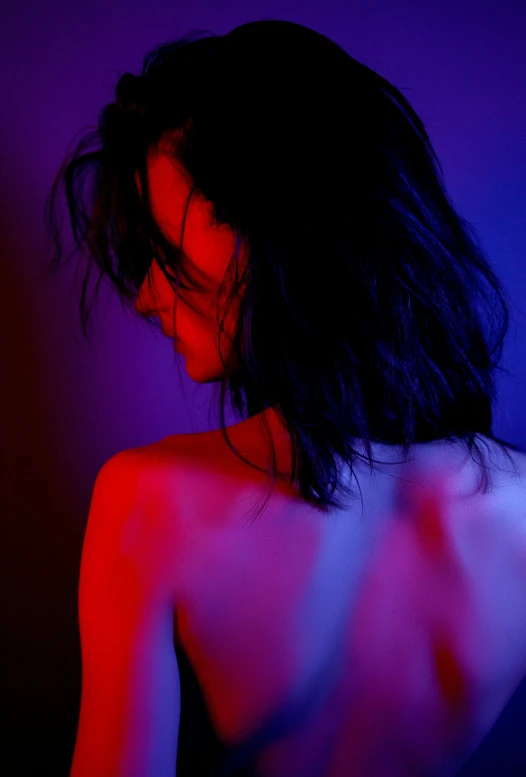 a woman standing in front of a red and blue light, inspired by Nan Goldin, unsplash, bare back, winona ryder, purple volumetric lighting, woman with black hair