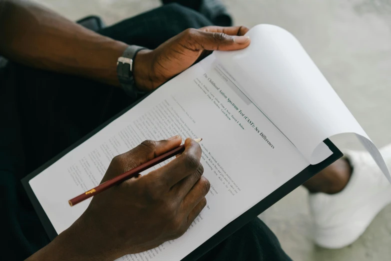 a person holding a pencil and writing on a piece of paper, jaylen brown, background image, high quality image, holding a giant book