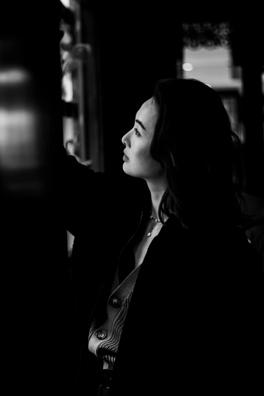 a black and white photo of a woman in a dark room, inspired by Peter Lindbergh, unsplash, lilly collins, woman's profile, medium format. soft light, gong li