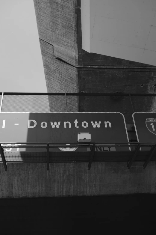 a black and white photo of a street sign, by Andrew Domachowski, unsplash, down-town, monorail, smol, downtown