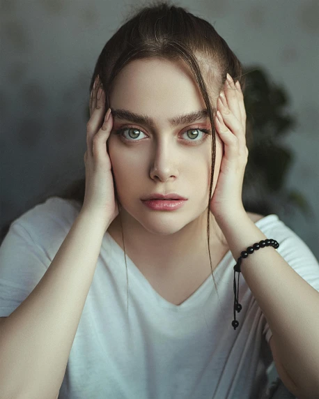 a woman sitting at a table with her hands on her head, inspired by Elsa Bleda, trending on pexels, renaissance, androgynous face, beautiful huge eyes, dasha taran, portrait of kim petras