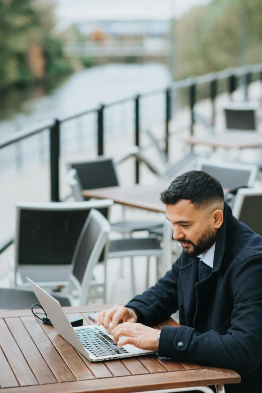 a man sitting at a table using a laptop computer, at the waterside, trending on attestation, multiple stories, gif