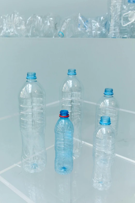 a group of plastic bottles sitting on top of a tiled floor, by Maeda Masao, plasticien, light blue water, plain background, standing water, upcycled