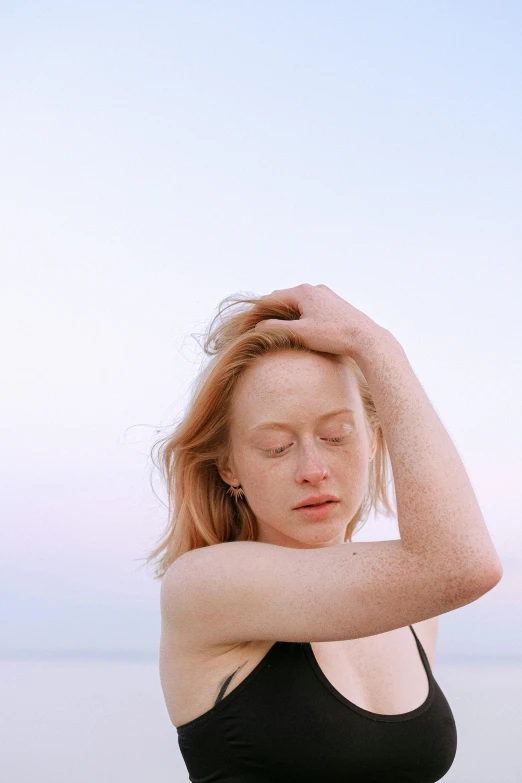 a woman standing on top of a beach next to the ocean, an album cover, by Carey Morris, trending on pexels, renaissance, freckled pale skin, miranda otto, depressed dramatic bicep pose, portrait of maci holloway