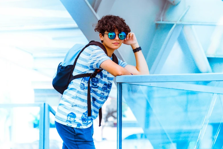 a man with a backpack leaning on a railing, inspired by John Luke, happening, wearing blue sunglasses, airport, avatar image, teenager