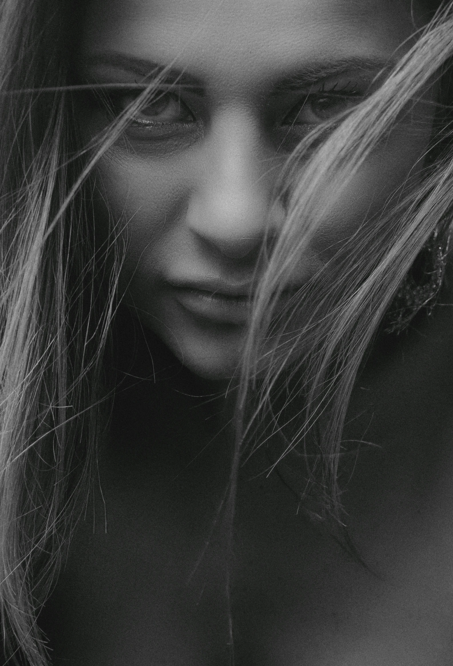 a black and white photo of a woman with long hair, a black and white photo, trending on pexels, close up of face, melancholic, windswept, a girl with blonde hair