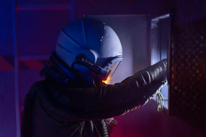 a man in a helmet welding a piece of metal, by David Donaldson, light and space, inside the tardis, neon operator margot robbie, 70's jetfighter pilot, extremely moody blue lighting