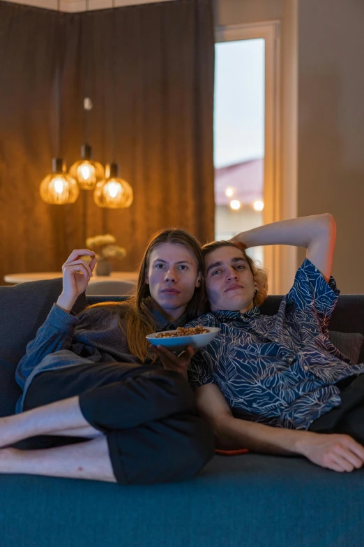 two women sitting on a couch watching tv, by Adriaen Hanneman, pexels contest winner, lights inside, male and female, relaxed pose, iceland