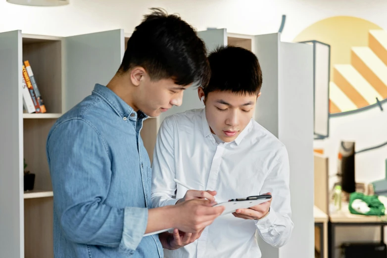 a couple of young men standing next to each other, by Jang Seung-eop, trending on pexels, happening, writing on a clipboard, avatar image, peter xiao, teaching