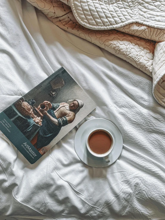 a book sitting on top of a bed next to a cup of coffee, inspired by Albert Anker, hyperrealism, magazine cover, instagram post, conde nast traveler photo, high angle shot