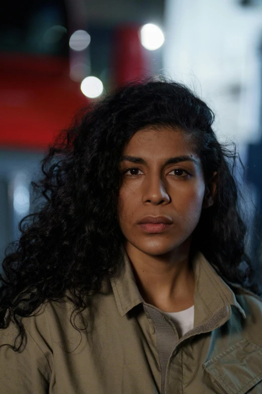 a close up of a person wearing a jacket, by Lily Delissa Joseph, smug look, stood in a cell, premiere, young middle eastern woman