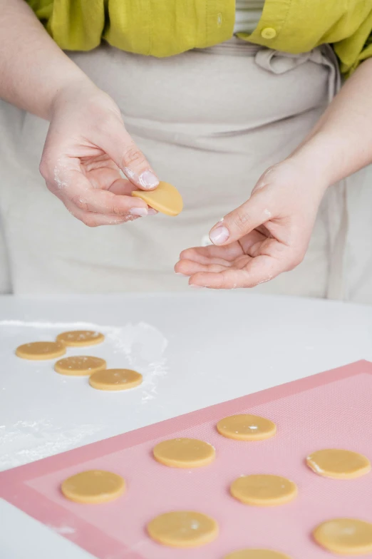 a woman holding a cookie in one hand and a cookie in the other, process art, silicone skin, instruction, tabletop, caramel
