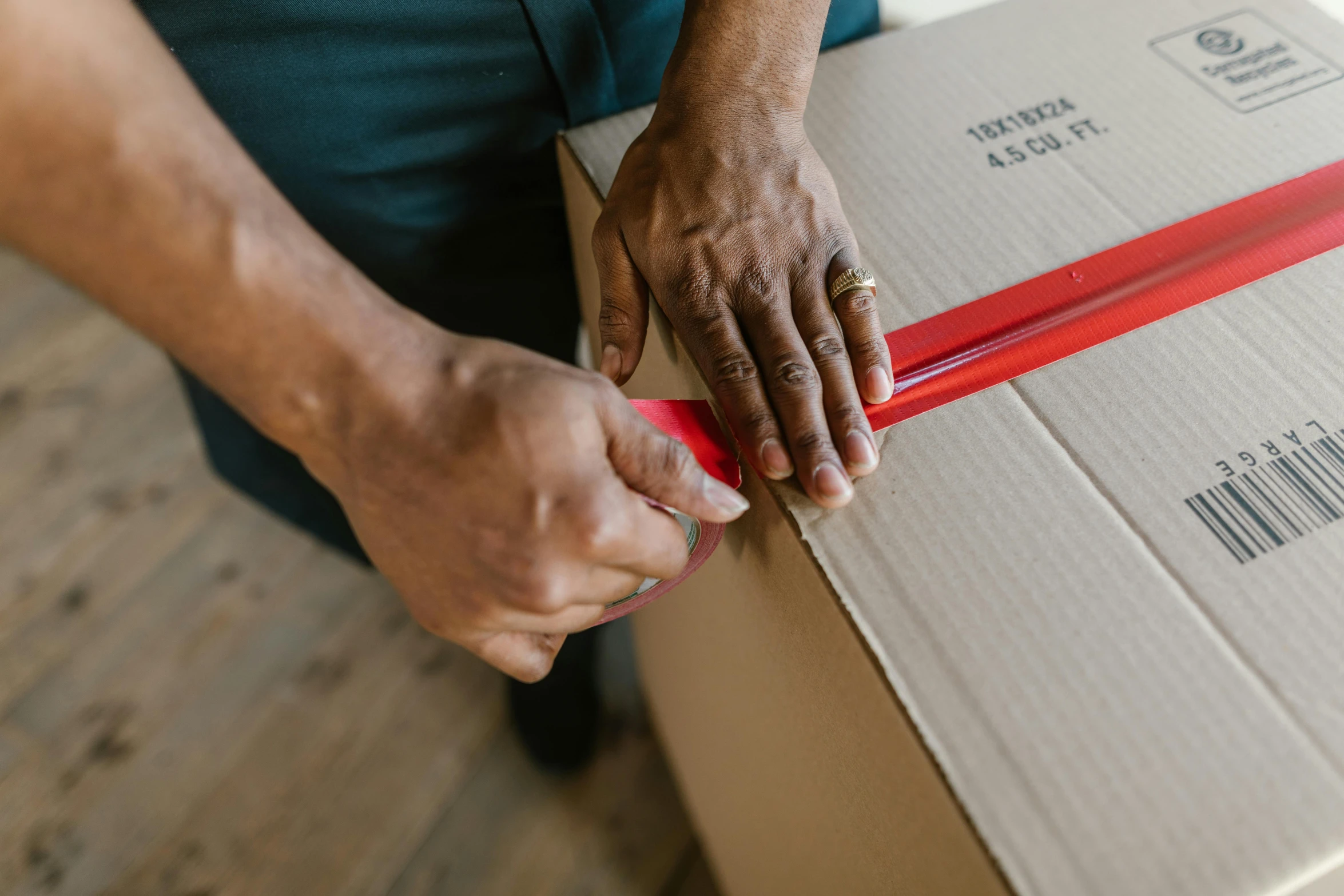 a man is wrapping a box with a red ribbon, by Everett Warner, pexels contest winner, hurufiyya, moving, with a sleek spoiler, thumbnail, brown