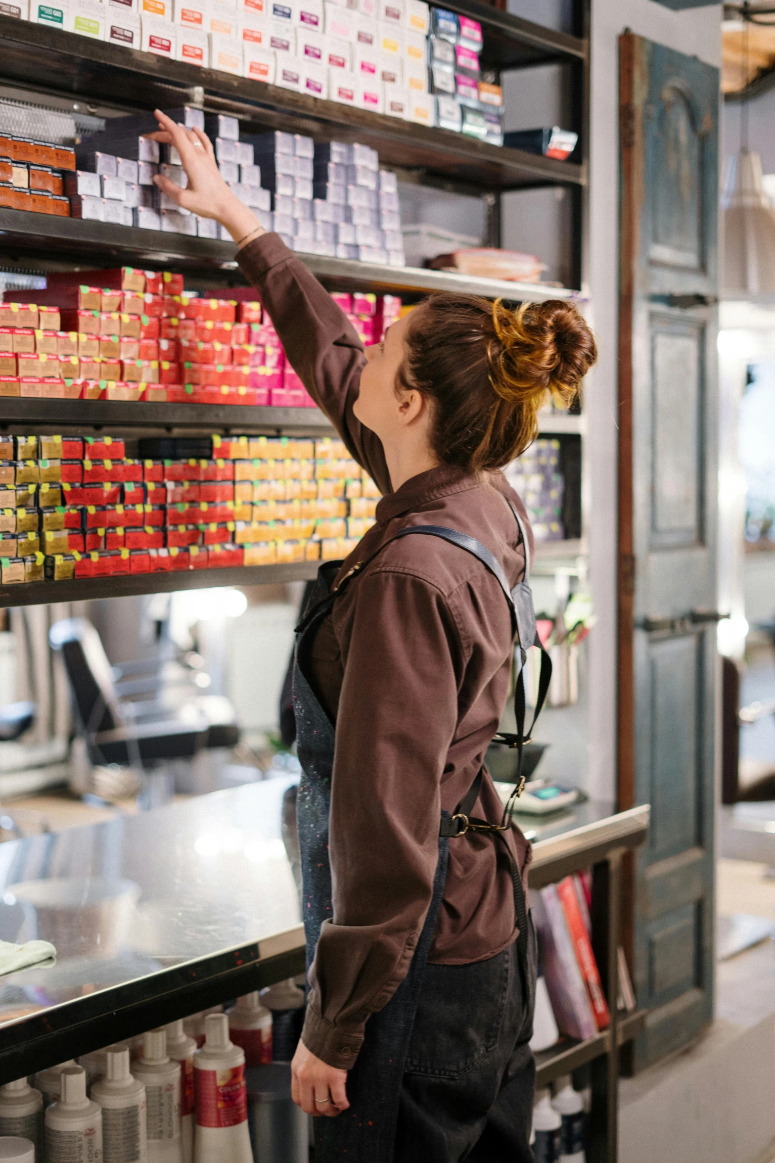 a woman that is standing in front of a shelf, hanging, at checkout, looking off to the side, satisfying