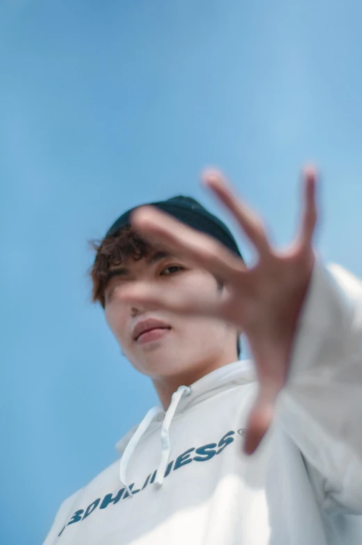a man in a white hoodie holding a tennis racquet, an album cover, by Jang Seung-eop, unsplash, holding his hands up to his face, blue skies, jungkook, headshot profile picture