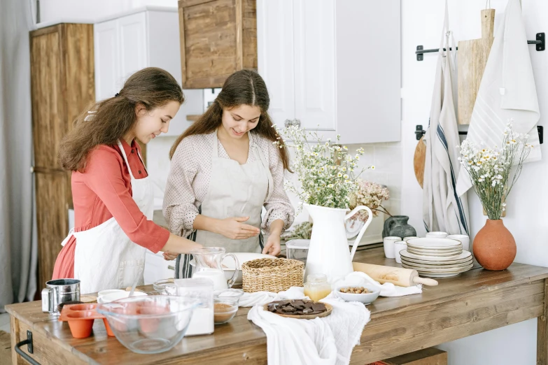 two women standing in a kitchen preparing food, trending on pexels, cottage core, background image, white tablecloth, baking artwork