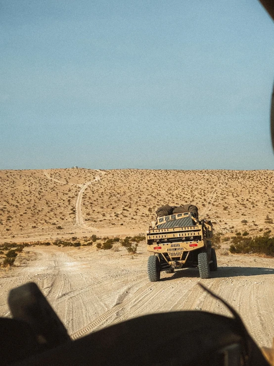 a truck driving down a dirt road in the desert, camouflaged gear, soft top, shot from the back, 2019 trending photo