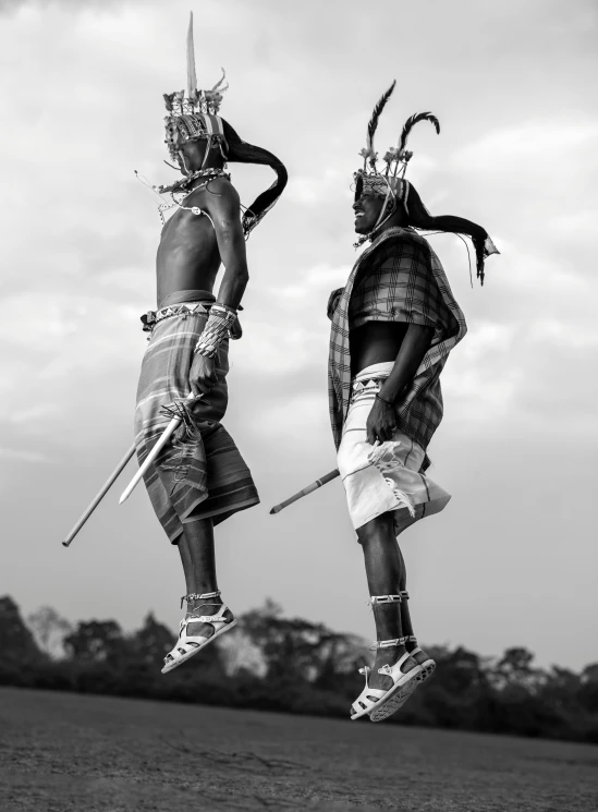 a couple of people that are jumping in the air, a black and white photo, by Ingrida Kadaka, afrofuturism, massai warrior, high quality upload, cgsociety - w 1 0 2 4 - n 8 - i, two horns