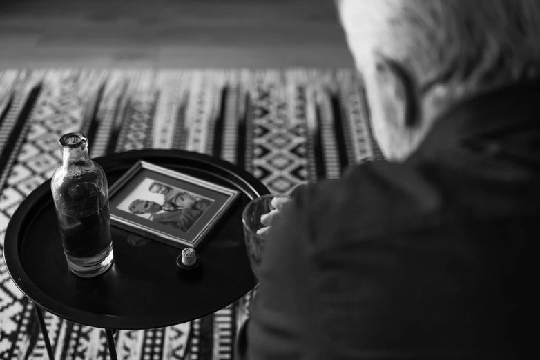 a black and white photo of a person sitting at a table, a black and white photo, funeral, father, tv still frame, turkey