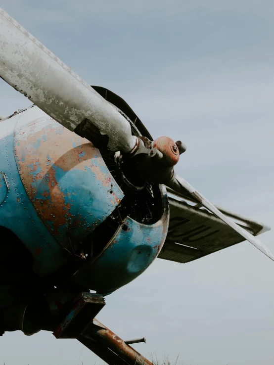 a propeller plane sitting on top of a grass covered field, a colorized photo, pexels contest winner, brown and cyan blue color scheme, looking down on the view, stålenhag, looking up at camera