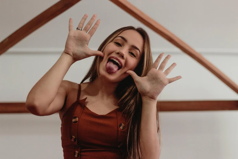 a woman making a funny face with her hands, trending on pexels, vanessa morgan, natural hands and arms, sydney hanson, indoor picture