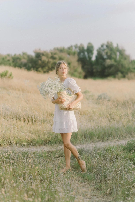 a woman standing in a field holding a bunch of flowers, lookbook, dressed in white, medium-shot, cute photo