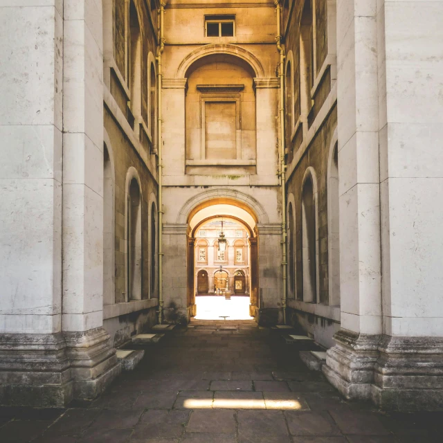 a hallway in a building with a clock on the wall, an album cover, by Christopher Wren, pexels contest winner, neoclassicism, giant archways, dappled in evening light, white building, college