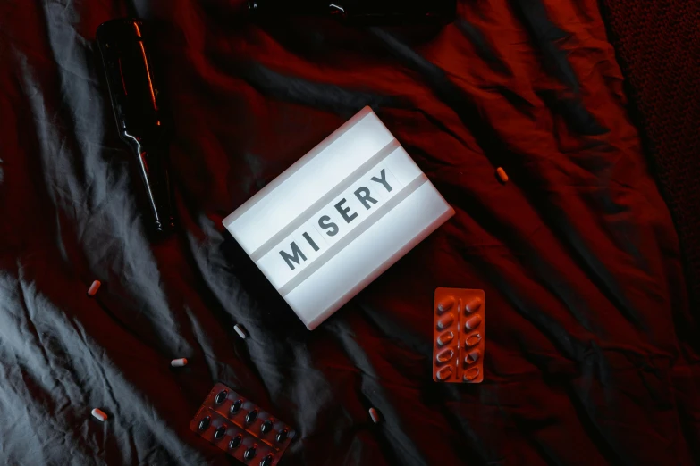 a book sitting on top of a bed next to a remote, an album cover, by Lisa Milroy, unsplash contest winner, mingei, dystopian toy, misery and despair, light box, neon sign