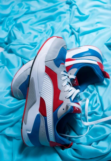 a pair of sneakers sitting on top of a blue sheet, trending on dribble, renaissance, brand colours are red and blue, based on a puma, frontal shot, fins