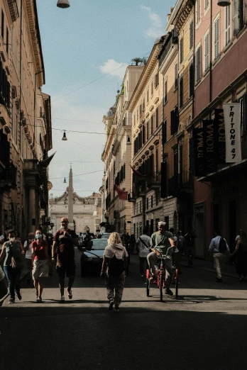 a group of people riding bikes down a street, by Alessandro Allori, pexels contest winner, neoclassicism, walking to the right, stores, square, summer afternoon