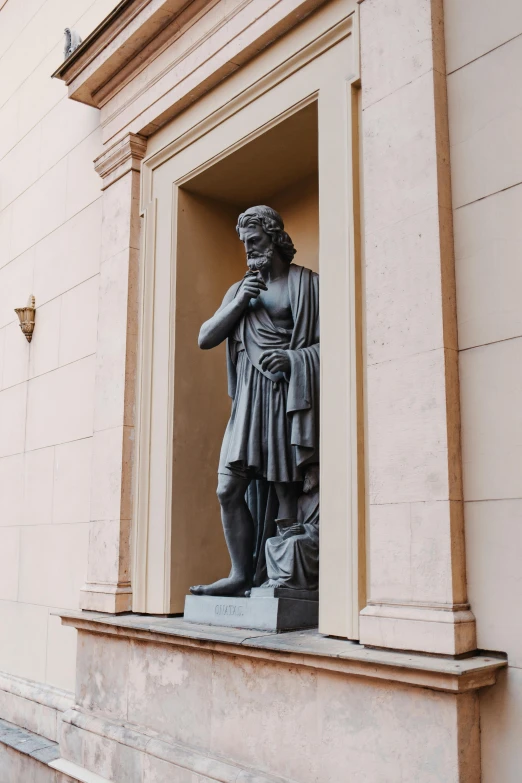 a statue of a man standing next to a building, inspired by Károly Markó the Elder, neoclassicism, doorway, archimedes, pondering, high-quality photo