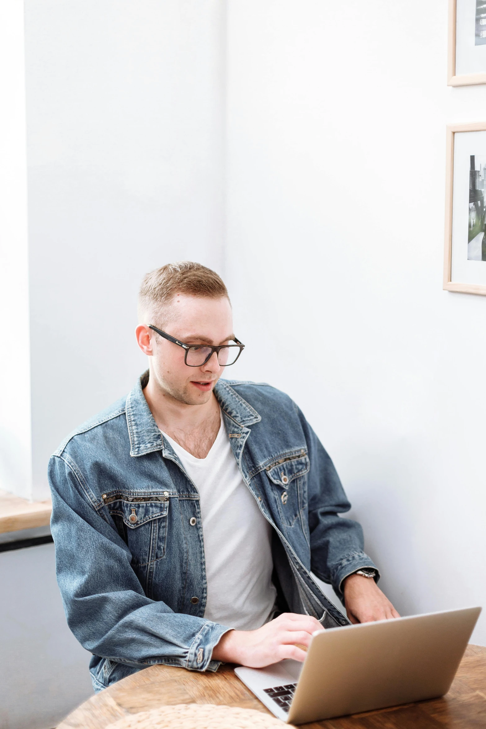 a man sitting at a table with a laptop, inspired by Daniel Ljunggren, trending on unsplash, wearing a shirt and a jean, smooth pale skin, profile image, standing in corner of room