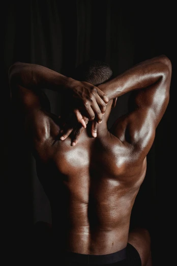 a man sitting in a chair with his back to the camera, inspired by Robert Mapplethorpe, pexels contest winner, renaissance, dark brown skin, marked muscles, covered in oil, arms open