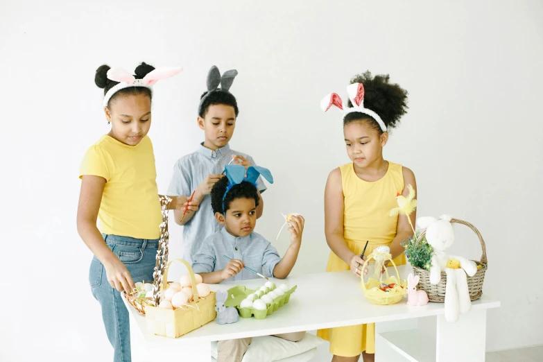a group of children standing around a table, pexels contest winner, bunny ears, yellow theme, crafts and souvenirs, actual photo