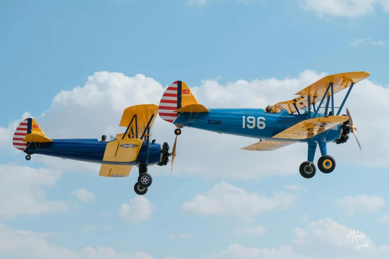 a blue and yellow airplane flying in the sky, by Dave Melvin, unsplash, photorealism, biplanes, albuquerque, camaraderie, slide show