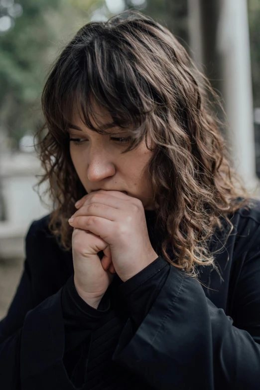 a woman sitting on a bench with her hand on her chin, a picture, inspired by Zoë Mozert, trending on pexels, praying posture, curly bangs, with depressive feeling, uncropped