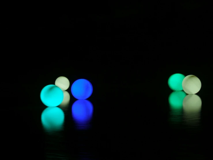 a couple of balls sitting on top of a table, inspired by Bruce Munro, interactive art, soft coloured gel lighting, blue and green water, volumetric lighting matte, some light reflexions