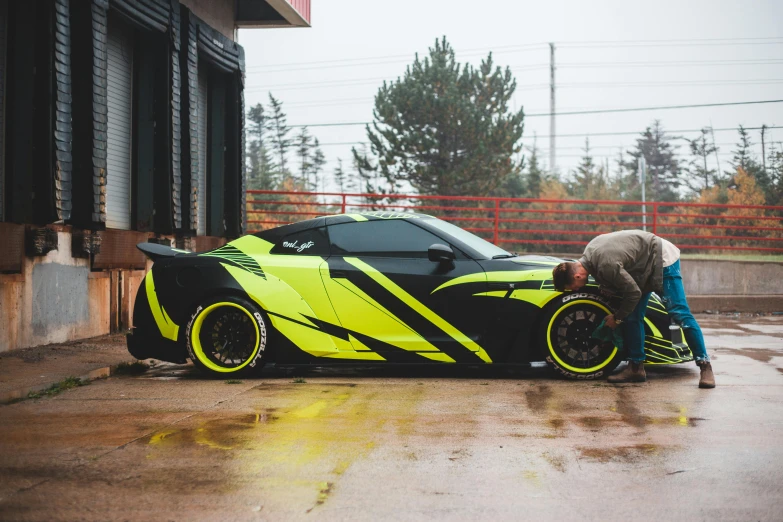 a man working on a yellow and black sports car, vector art, by An Gyeon, unsplash, street art, full body shot 4k, just after rain, christian cline, samurai vinyl wrap