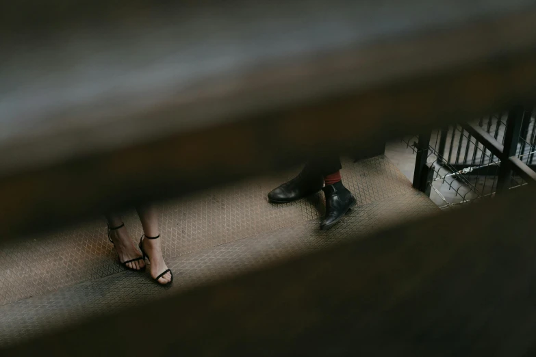 a couple of people standing next to each other, inspired by Louis Stettner, trending on unsplash, renaissance, wooden stairs, leather shoes, high-angle, low-light