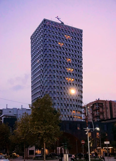 a tall building sitting in the middle of a city, by Niko Henrichon, brutalism, at twilight, low quality photo, no cropping, front lit