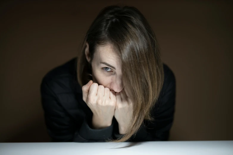 a woman sitting in front of a laptop computer, a picture, trending on pexels, hyperrealism, scared face, hand on table, moody hazy lighting, high quality photo