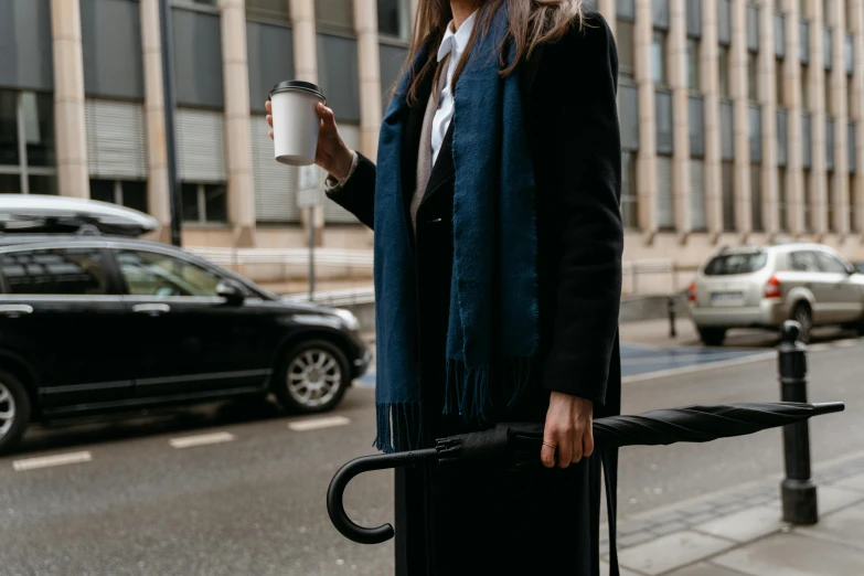 a woman holding a cup of coffee and an umbrella, pexels contest winner, holding a briefcase, black car, wearing fluffy black scarf, high quality product image”