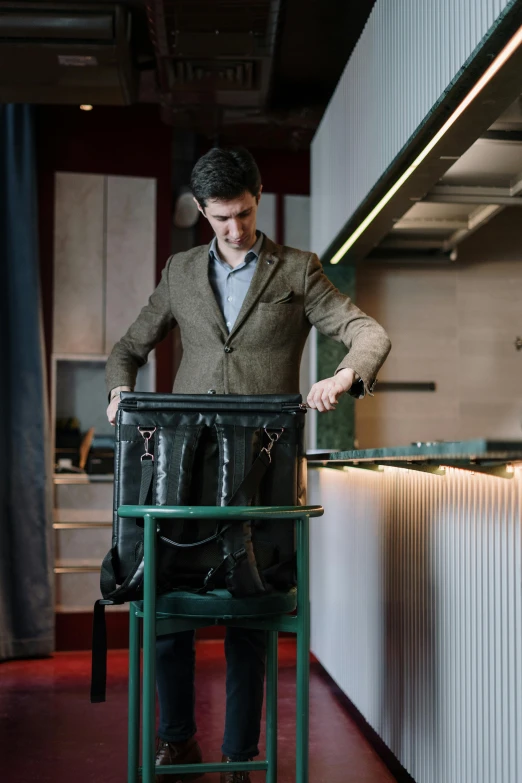 a man standing on top of a green chair, in suitcase, blacksmith product design, with a backpack, indoor