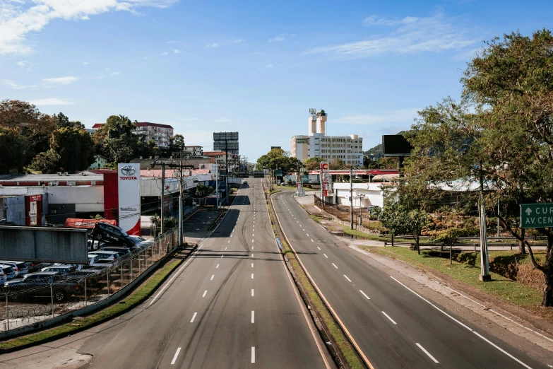 a city street filled with lots of traffic next to tall buildings, by Ceferí Olivé, unsplash, hyperrealism, driving through a 1 9 5 0 s town, puerto rico, empty road in the middle, covid