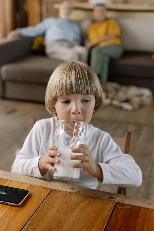a little boy sitting at a table drinking a glass of milk, pexels, sitting at a computer, multiple stories, thumbnail, 12