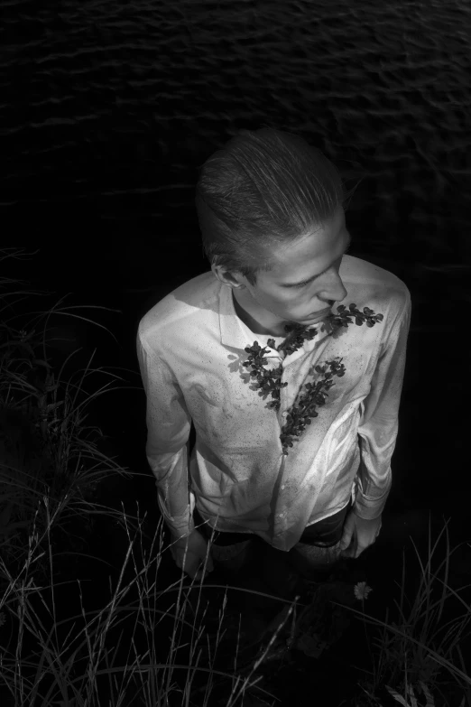 a black and white photo of a man standing in the water, a black and white photo, inspired by Peter Basch, tumblr, standing in a field with flowers, nighttime!, a blond, hedi slimane