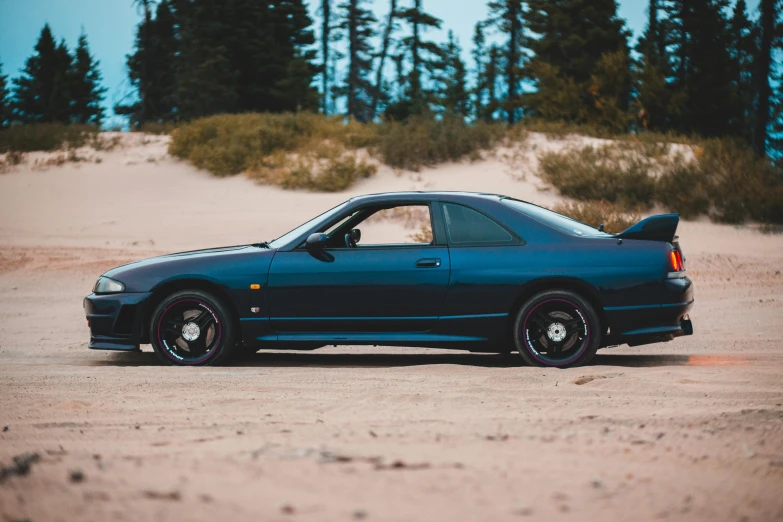 a blue car parked on top of a sandy beach, a portrait, unsplash, in a modified nissan skyline r34, profile image, 2263539546], mid body