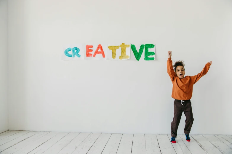 a little boy standing in front of a sign that says creative, a child's drawing, pexels contest winner, sitting in an empty white room, jumping towards viewer, crafts, promotional image