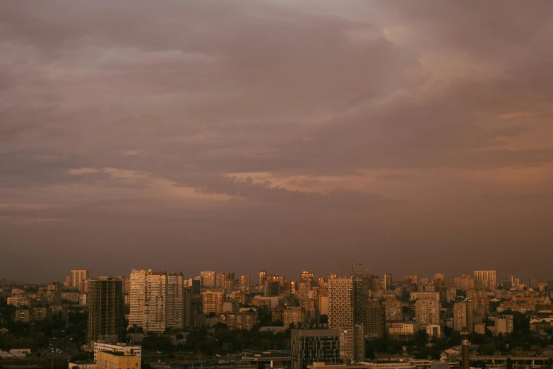 a city filled with lots of tall buildings under a cloudy sky, by Attila Meszlenyi, golden hour photograph, azamat khairov, pale beige sky, pink skies